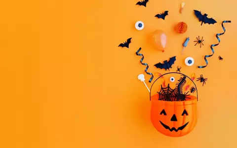 Halloween pumpkin bucket with treats and decorations spilling out