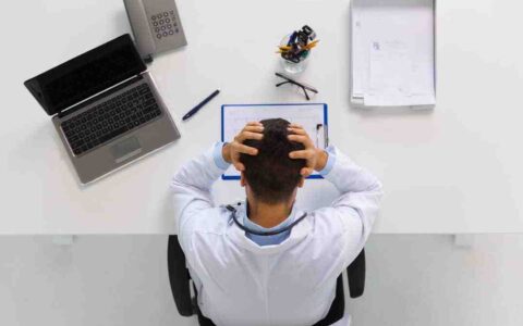 Man holding his head in his hands looking at paper on desk