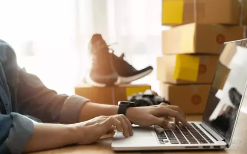 Individual in front of laptop with stock around him being sold online