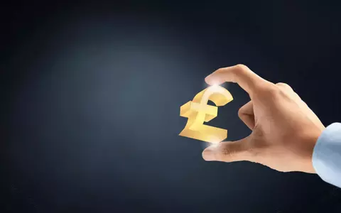 Hand holding out a golden GBP sign