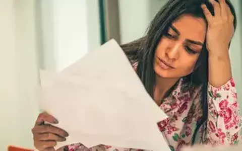 Stressed Indian woman looking at papers with hand on head