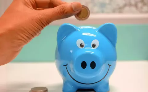 Hand putting coin in blue piggybank