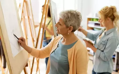 Senior Woman Drawing On Easel At Art School Studio