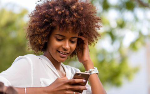 Woman outside looking at phone with content and happy smile
