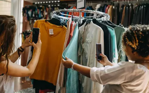 Women browsing and taking pictures of vintage clothing on rack